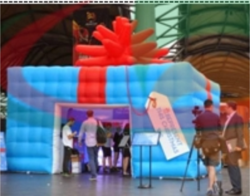 A large inflatable structure resembling a gift box in a vibrant setting.
