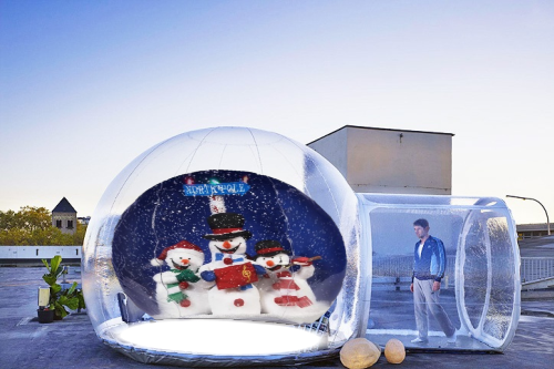 Single Entrance Snow Globe A person stands beside a large snow globe featuring snowmen against a winter backdrop.