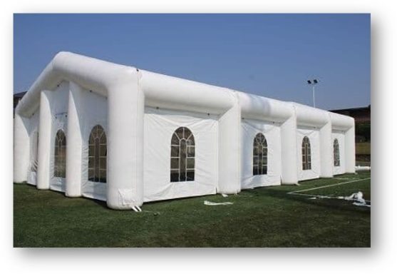 An inflatable white marquee with arched windows set up on grassy ground.